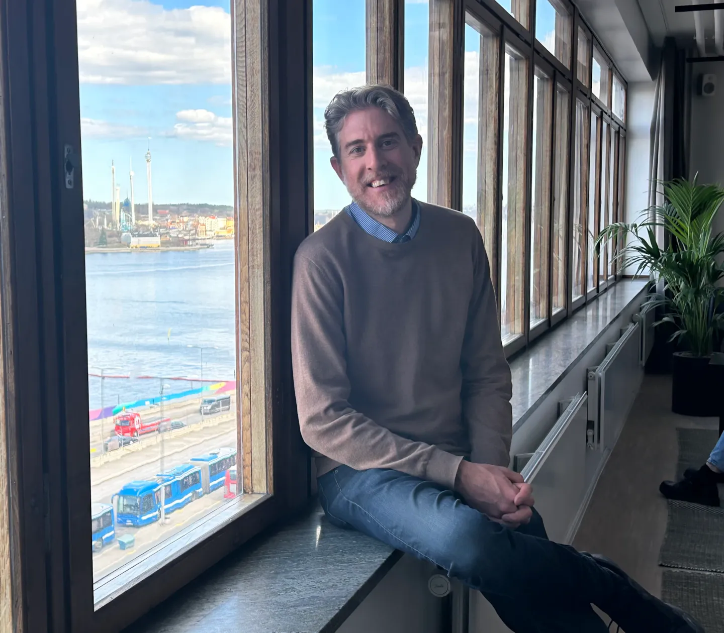 Linus sitter i fönstret på nya kontoret med Stockholms inlopp i bakgrunden