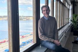 Linus sitter i fönstret på nya kontoret med Stockholms inlopp i bakgrunden