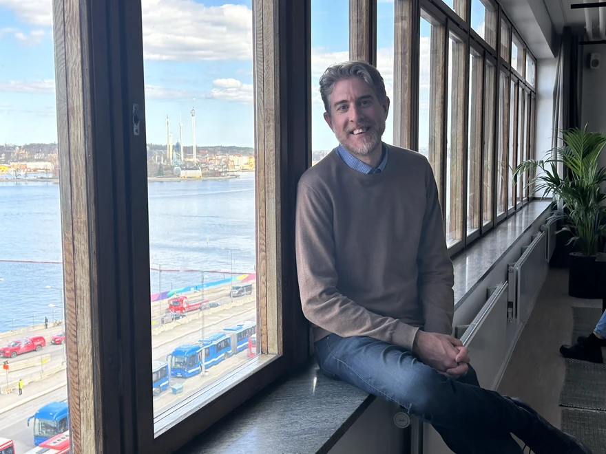 Linus blickar ut genom fönster i nya kontoret NOVA house