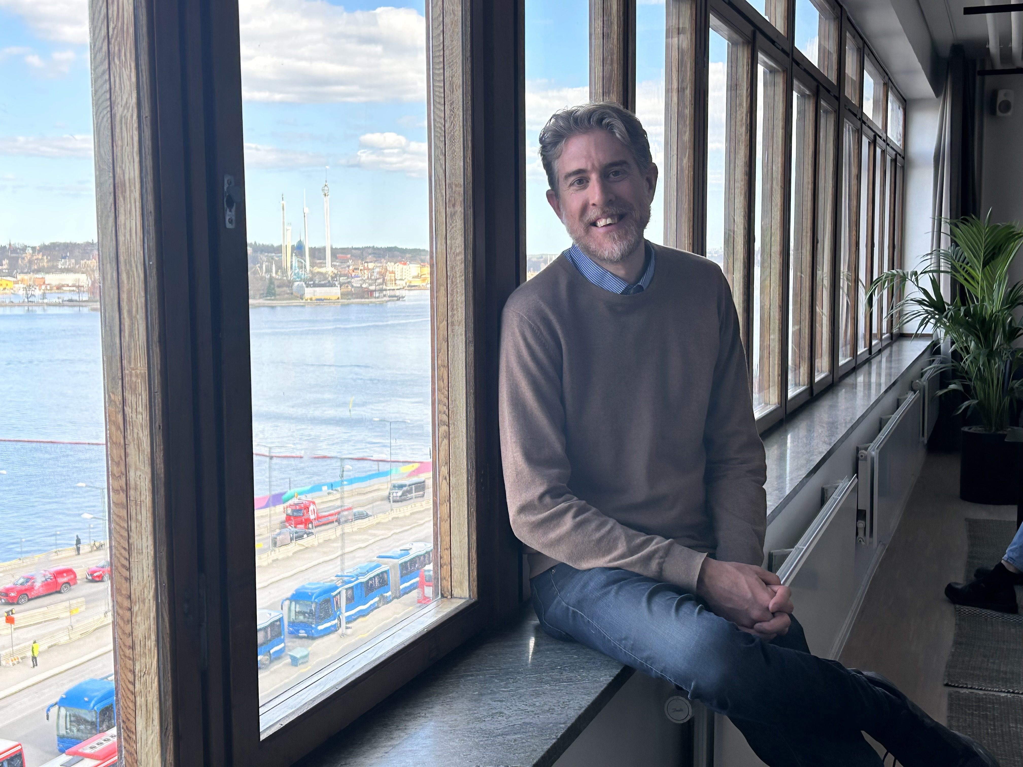 Linus blickar ut genom fönster i nya kontoret NOVA house