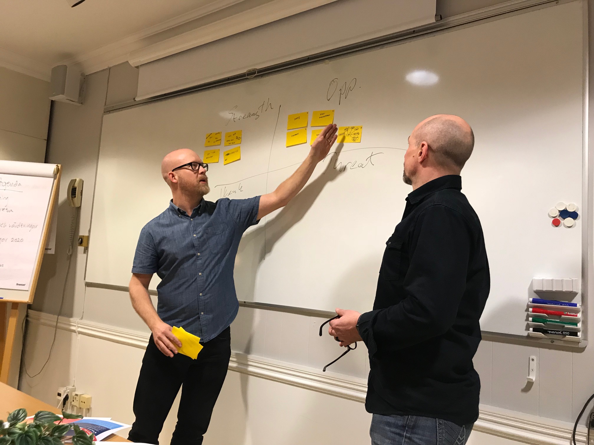2 men in front of a whiteboard with postit notes