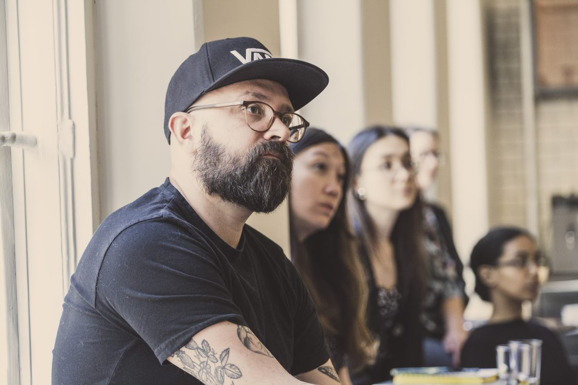 Johan lyssnar i ett konferensrum med människor i bakgrunden