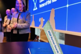 Crystal Award med "2025 Partner Awards" graverat, placerat på ett bord framför en presentationsskärm med "Epimova Customer Choice Partner of the Year." Folk som står i bakgrunden.