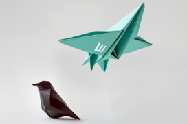 Sitting origami bird and a flying origami airplane