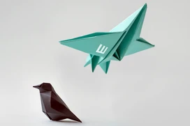 Sitting origami bird and a flying origami airplane