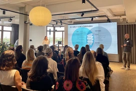 Publiken tittar på en affärspresentation om AI-sökning och SEO i ett modernt konferensrum med en stor projicerad bild och högtalare.