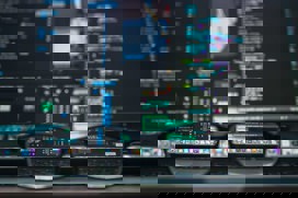 Black computer screen with lines of code and a pair of glasses lying in front
