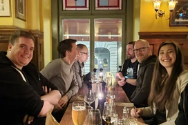 En grupp människor som sitter vid ett bord i en restaurang och skrattar, med drycker framför sig