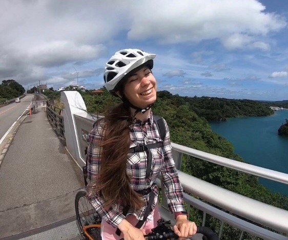 Smiling girl bike riding over bridge