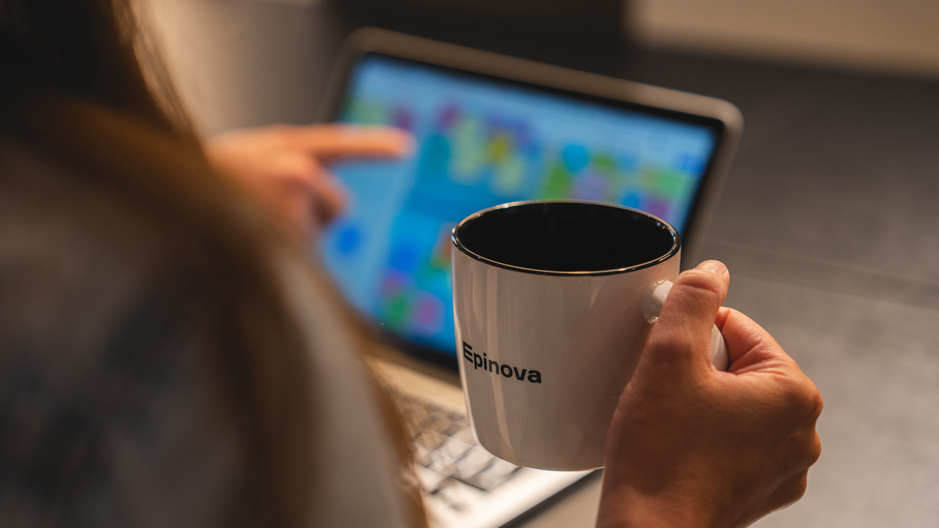 Person med kaffekopp i handen framför en datorskärm