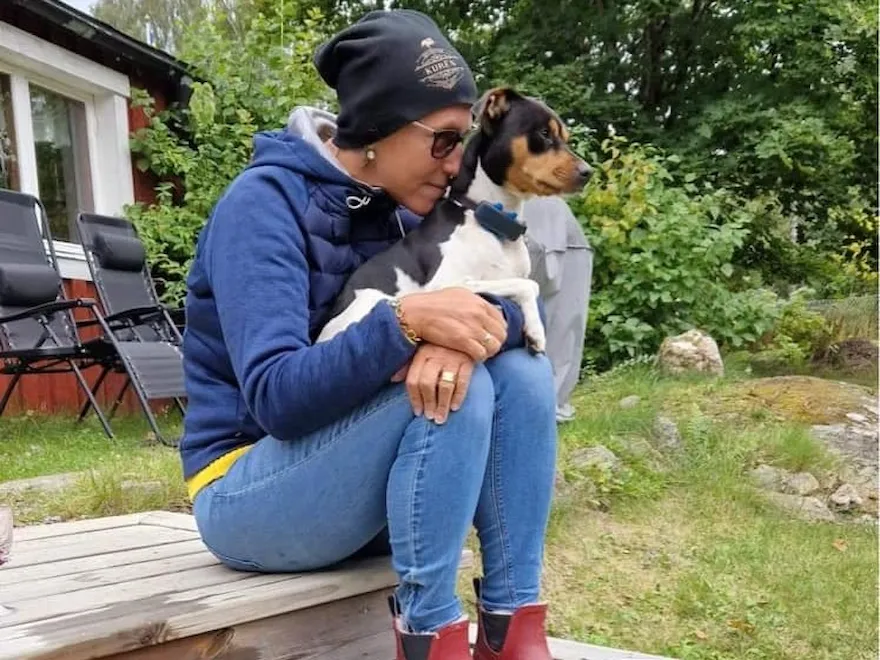 Ulrika sittandes på altanen vid fritidshuset med hunden Herbert i famnen
