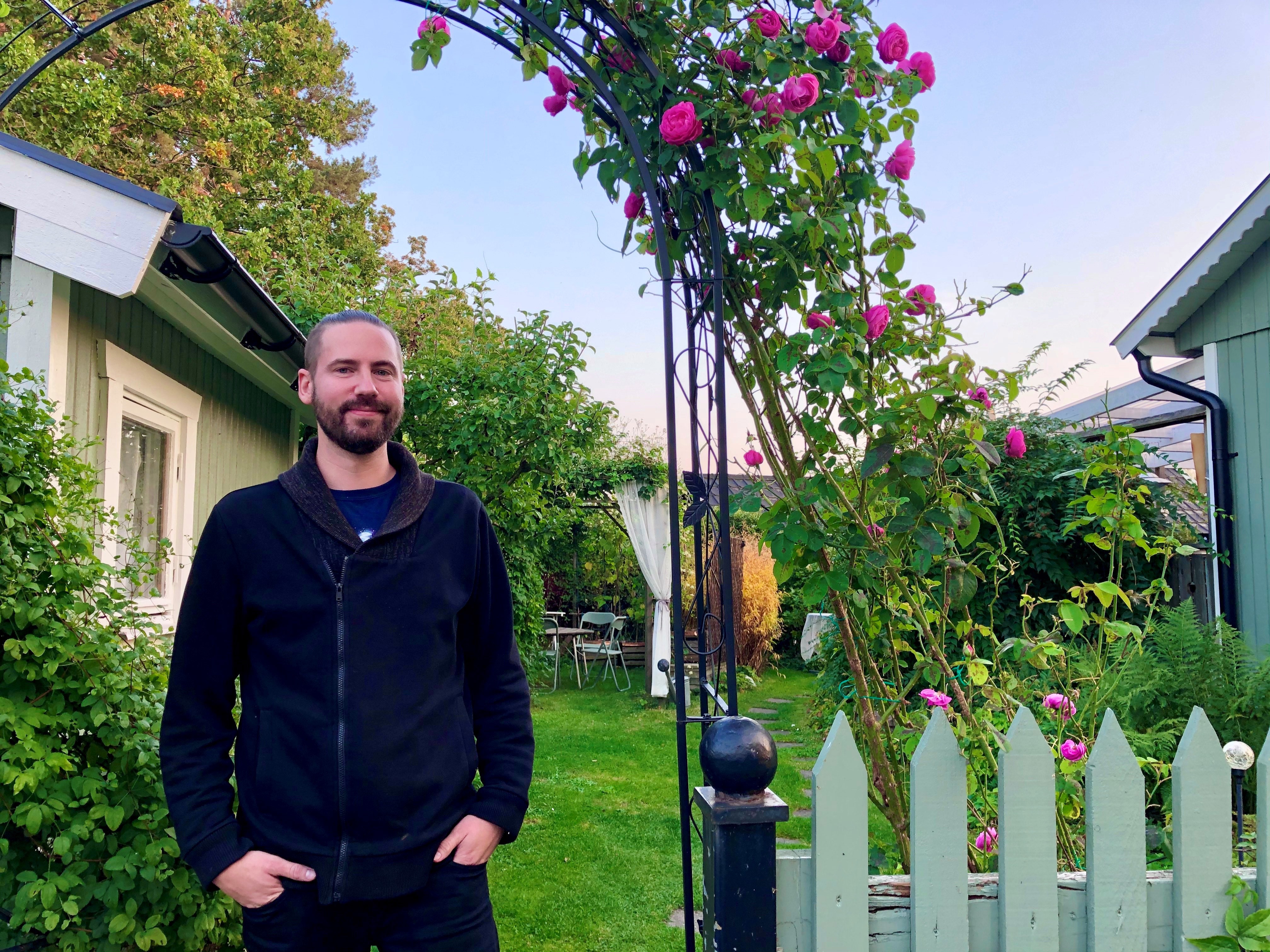 Wezz i sin trädgård med grön gräsmatta och rosor