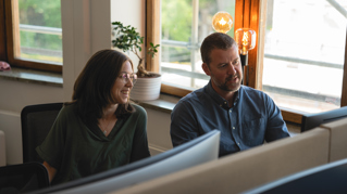 Two people conversing at a computer screen