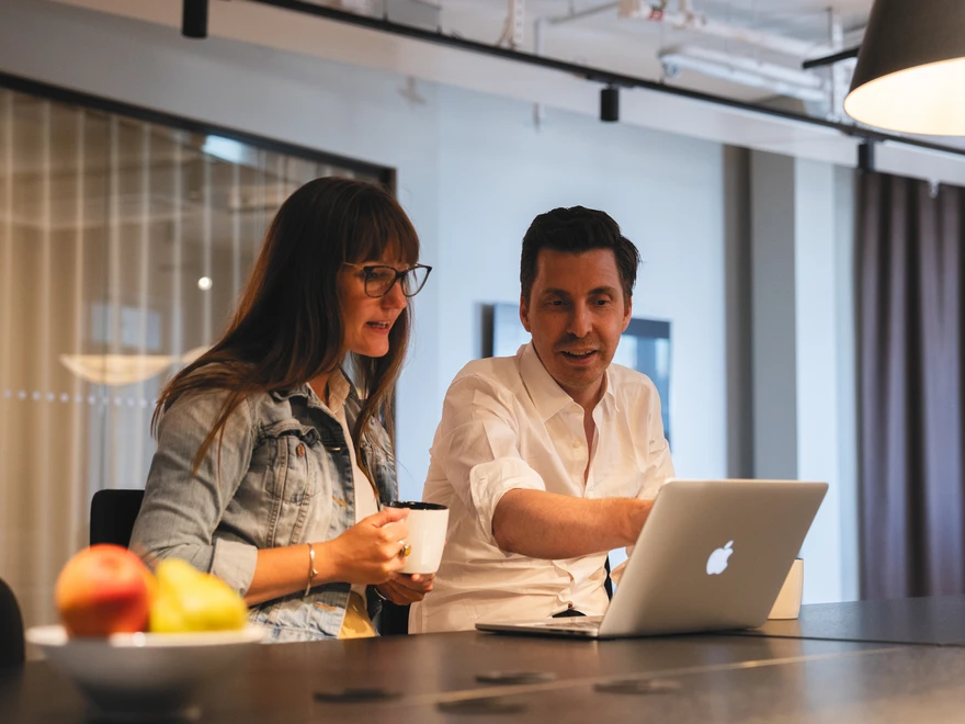 Two people are sitting at a computer discussing something together.