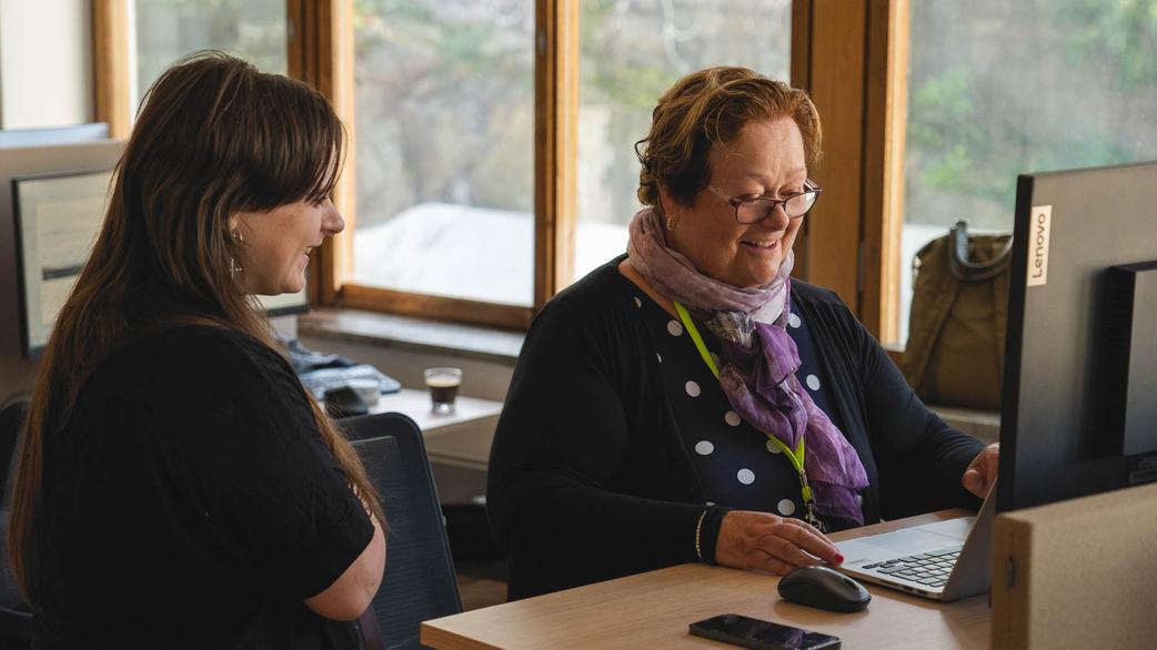 Två personer som står vid ett skrivbord och tittar på samma skärm
