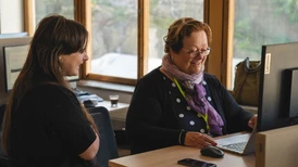 Två personer som står vid ett skrivbord och tittar på samma skärm