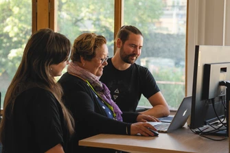 Tre kollegor vid ett skrivbord framför en datorskärm