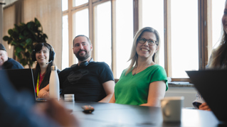 Smiling persons at a table in a conference room
