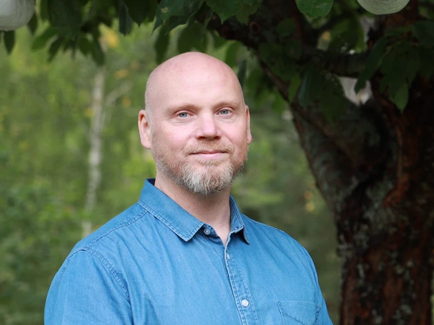 Joacim outdoors with trees and greenery in the background