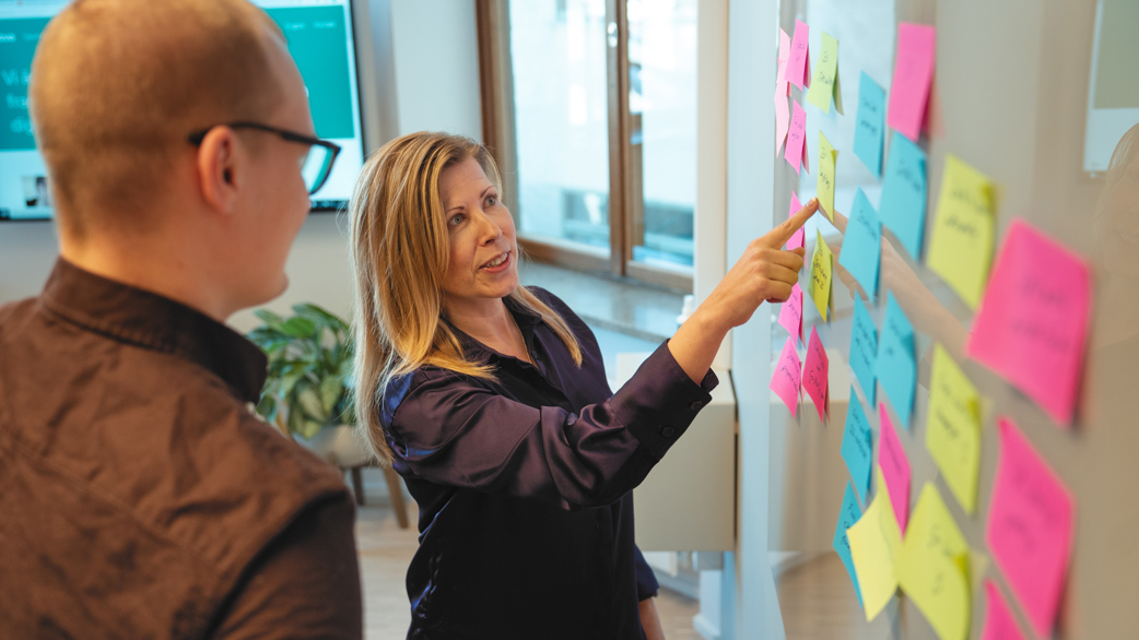 Two people working at whiteboard with post-it notes