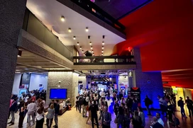 People in a large hallway with blue light and red walls