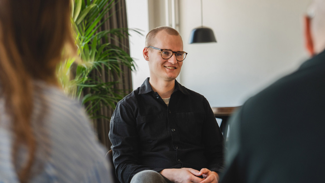 Joakim Sommar smiling with colleagues in a meeting