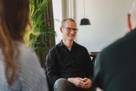 Joakim Sommar leende mot kollegor i möte