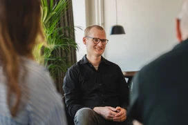 Joakim Sommar leende mot kollegor i möte